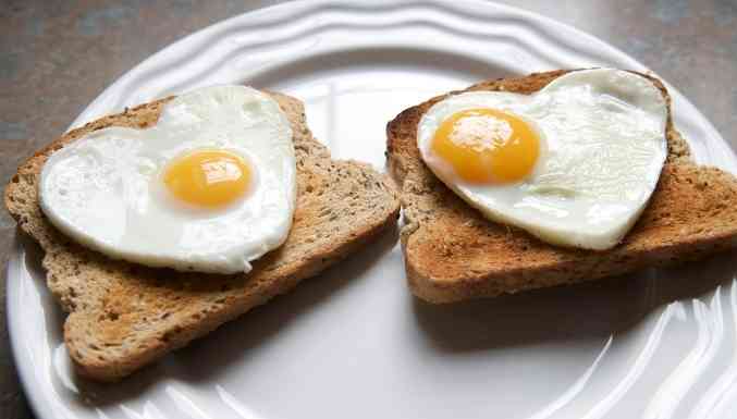 Prato com duas torradas e ovos fritos em forma de coração por cima